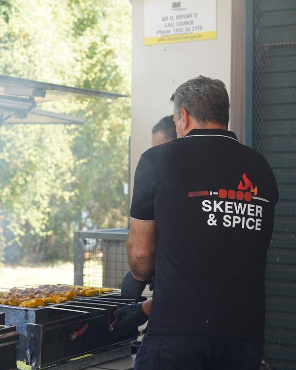 A Skewer & Spice chef working the smoking grill beside the catering trailer